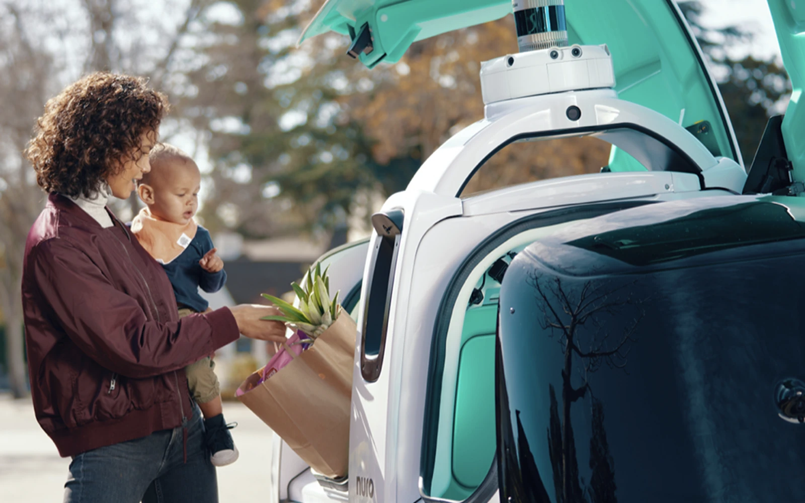 A customer receiving a delivery from the Nuro vehicle compartment